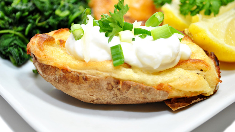 A twice-baked potato with sour cream and chives on top of it