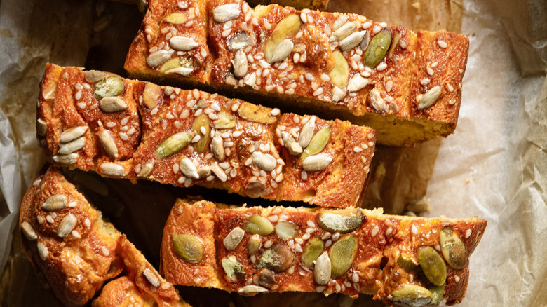 Slices of pumpkin bread topped with pumpkin seeds, sesame seeds, and sunflower seeds