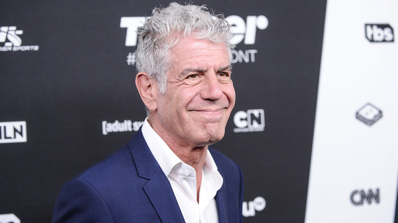 Anthony Bourdain smiling at a red carpet event wearing a blue suit