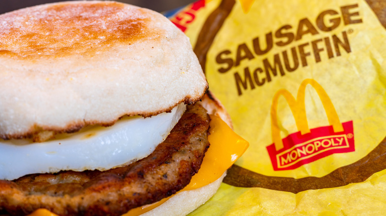 McDonalds Sausage McMuffin breakfast sandwich with egg and cheese displaying wrapper featuring Golden Arches logo and monopoly promotion branding.