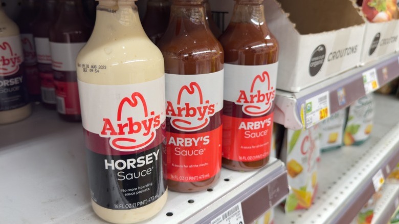 Several bottles of Arby's sauce on a supermarket shelf.