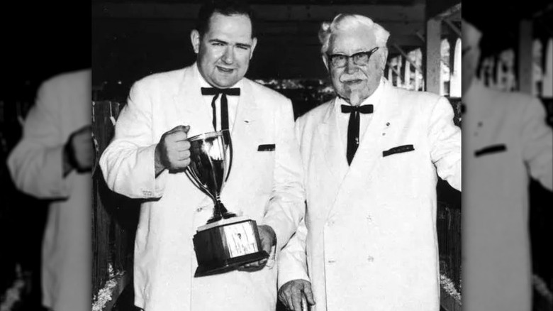 Dave Thomas (left) holding a trophy next to Colonel Harlan Sanders.