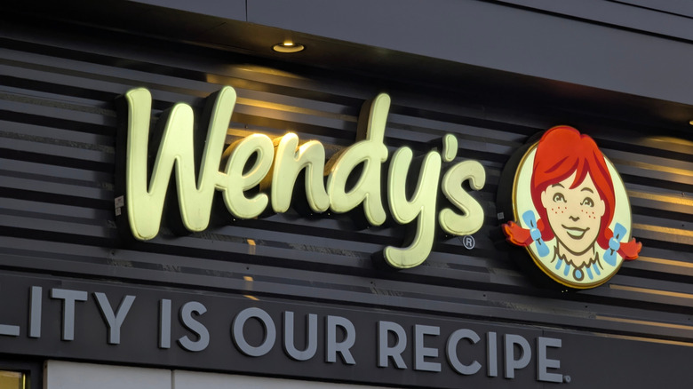 The exterior sign of a Wendy's location with the lights above it on
