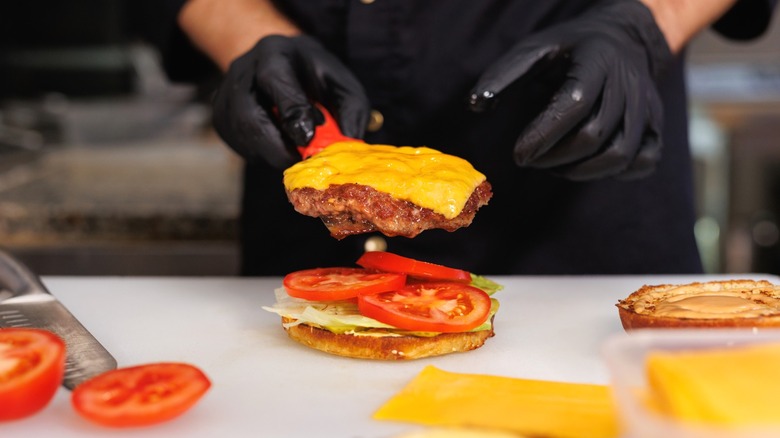 A short order cook preparing a fast food burger.