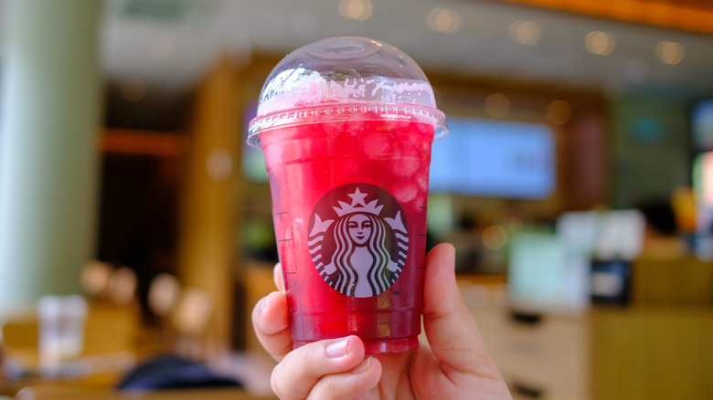 Hand holding pink hibiscus iced tea Starbucks drink