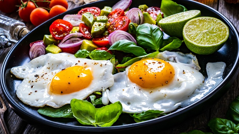 Fried eggs and salad in black dish