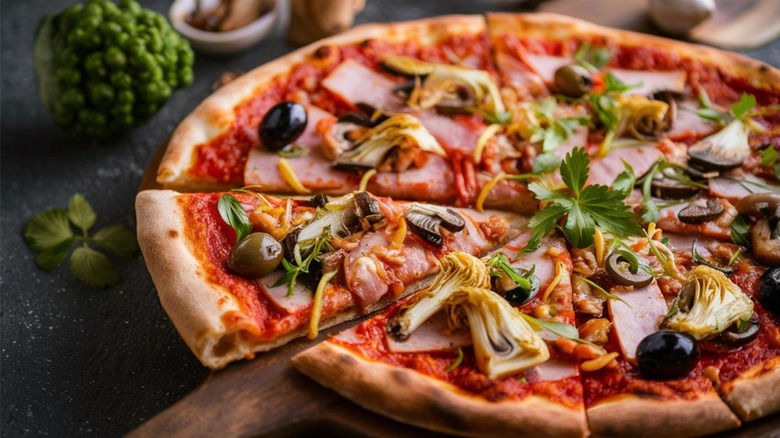 Pizza with various toppings: tomato sauce, cheese, black olives, Canadian bacon, mushrooms and quartered artichokes