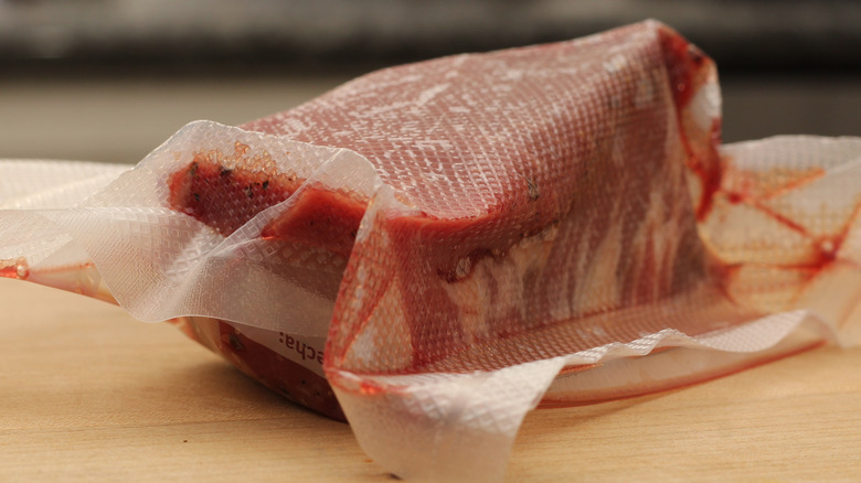 A close-up of vacuum-sealed raw beef fillets on kitchen countertop.