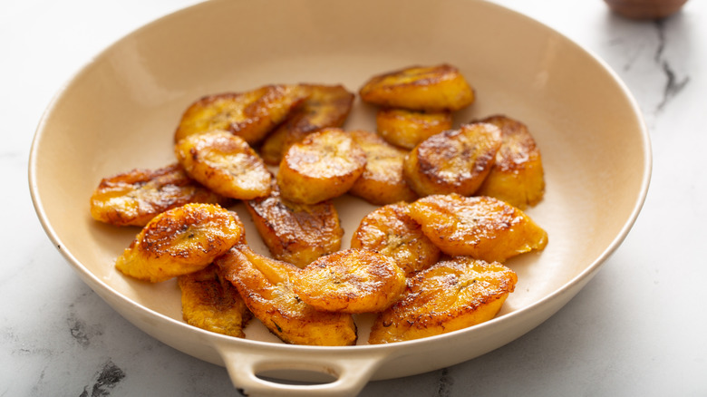 Caramelized banana slices rest in a baking dish on a marble countertop