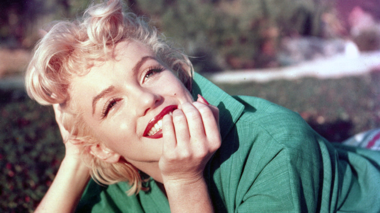 Marilyn Monroe in green shirt smiling with hand on chin