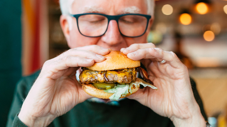 Man biting into burger with eyes shut