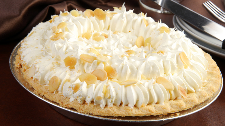 Uncut pie with ornate whipped cream topping on table.