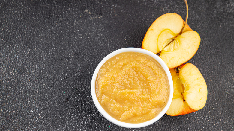 A bowl of applesauce garnished with two apple halves