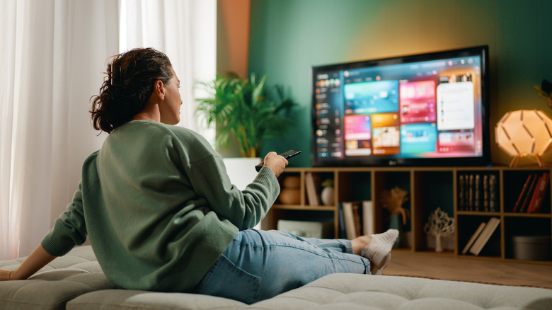 A woman sitting on a couch watching television.