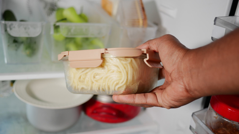 A person placing leftovers in the fridge