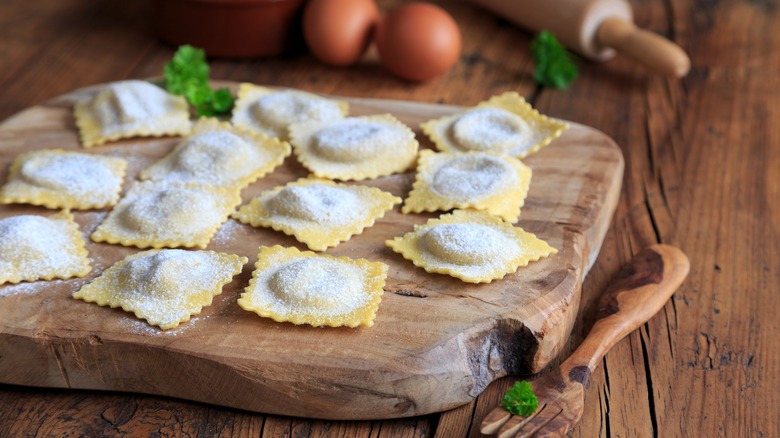 Square, uncooked ravioli on a rustic wooden board