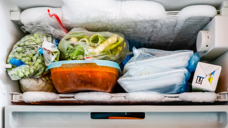 A freezer packed with food containers and ice build-up