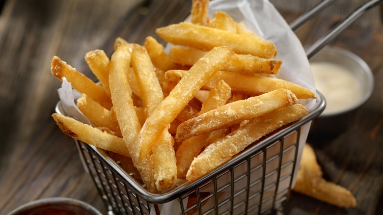 A closeup of french fries in paper-lined wire basket