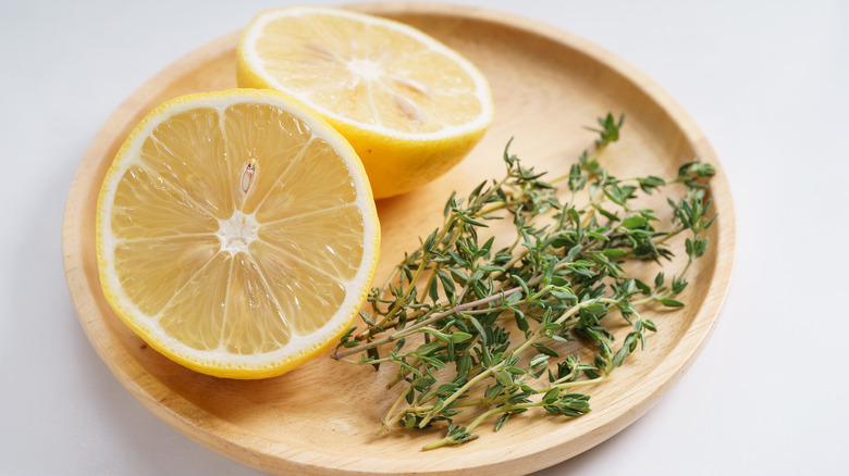 Wooden plate with halved lemon and fresh thyme
