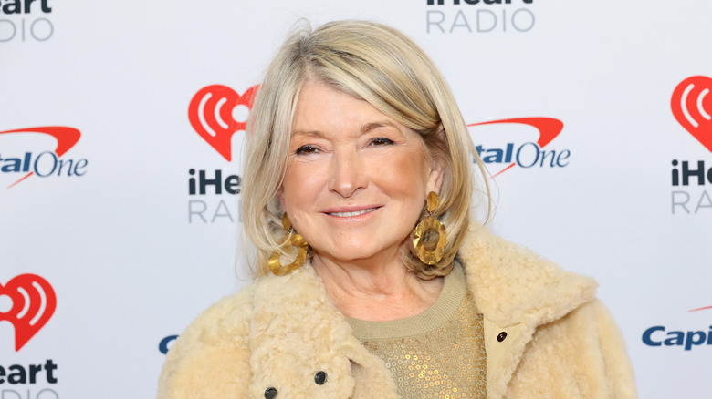 Martha Stewart wearing large gold earrings, a gold sequin top, and a fuzzy tan jacket