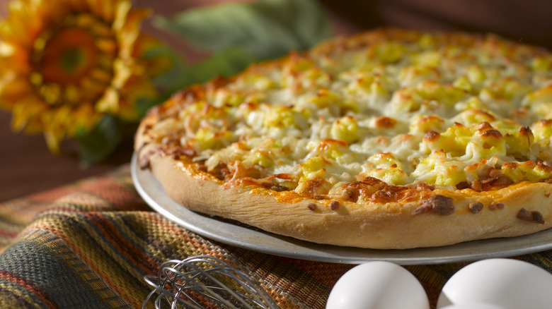 Breakfast pizza with eggs and cheese on a kitchen table