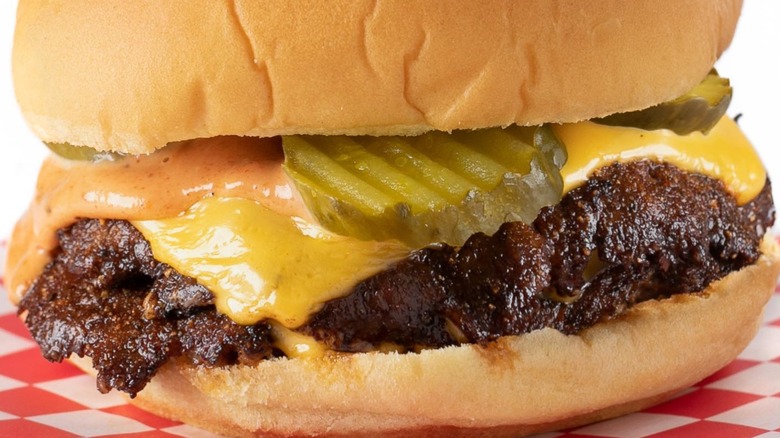 Closeup of smashed burger with cheese, sauce, pickles