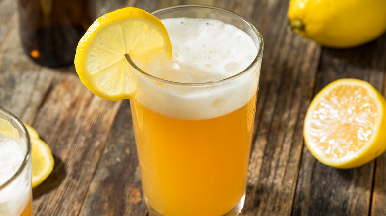 Beer shandy in a pint glass garnished with a lemon slice