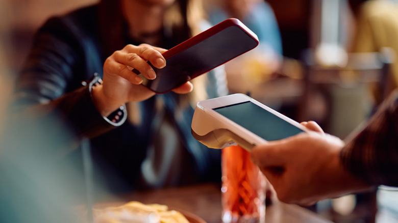 A bar patron pays for a drink using their phone
