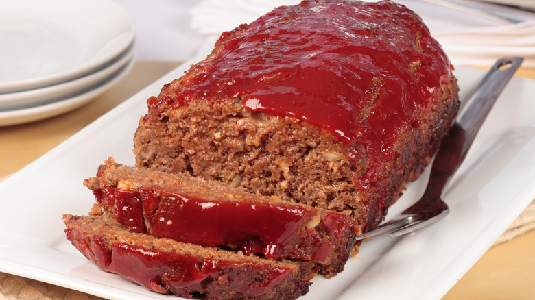 ketchup-topped meatloaf on a rectangular white plate with a fork on the side