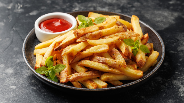 Homemade french fries with ketchup and basil garnish