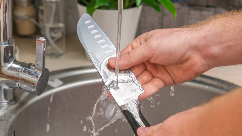 running metal knife under hot water