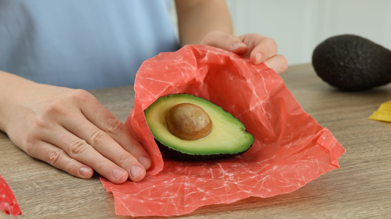 Person wrapping avocado in beeswax paper