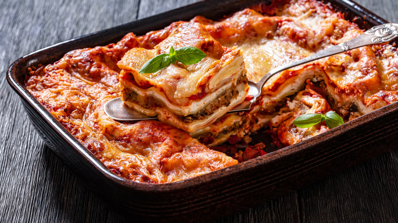 A tray of lasagna with one piece scooped out