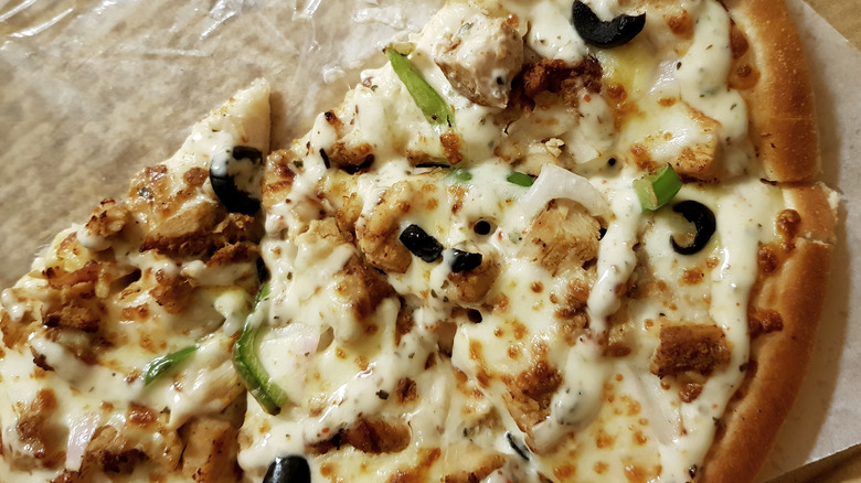 Leftover slices of chicken pizza with white sauce in a cardboard box