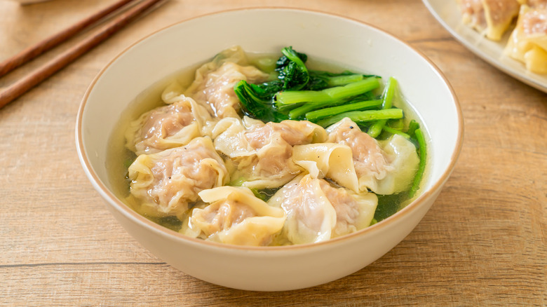 A hot bowl of dumpling soup with wilted greens
