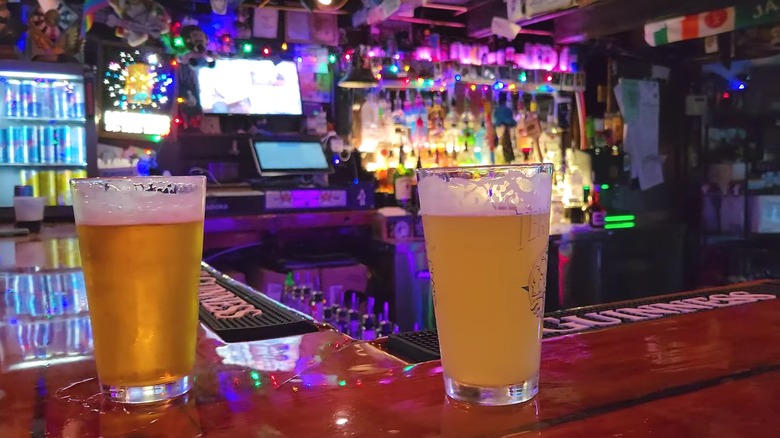 Two pints of beer sitting on a bar.