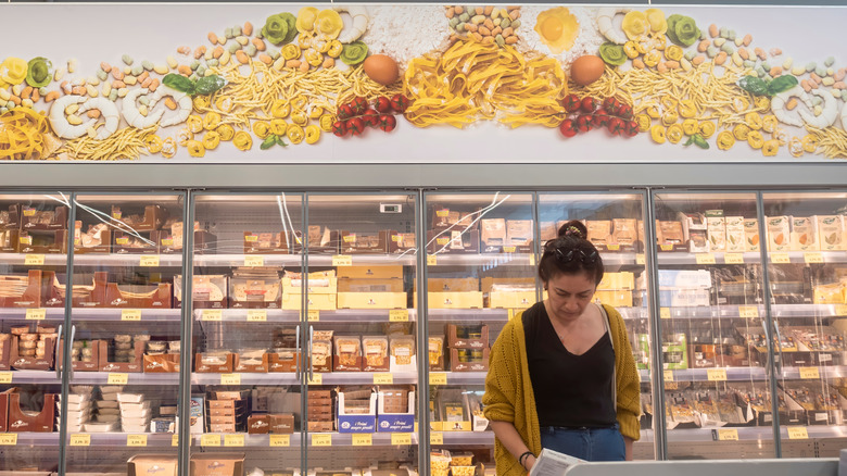 Shopper in front of fresh pasta refrigerated section at grocery store