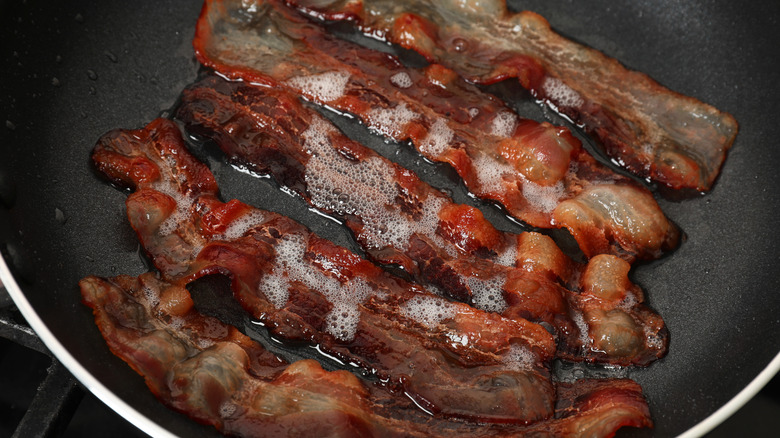 Five slices of greasy bacon in a skillet