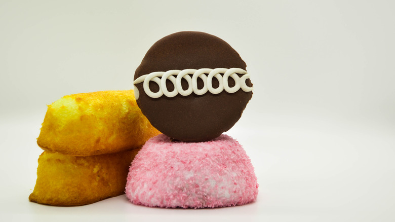 Several different kinds of snack cakes outside of their packaging stacked on top of each other.