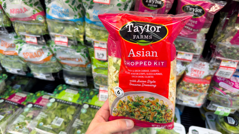 Someone holding a bagged salad in a supermarket