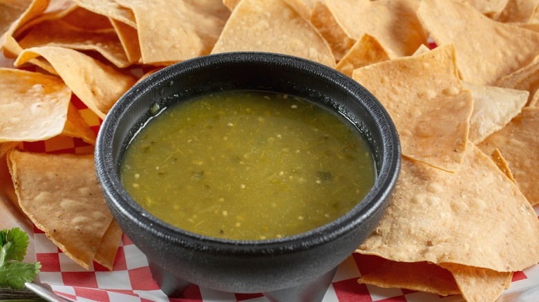 A closeup view of salsa verde on a plate of tortilla chips.
