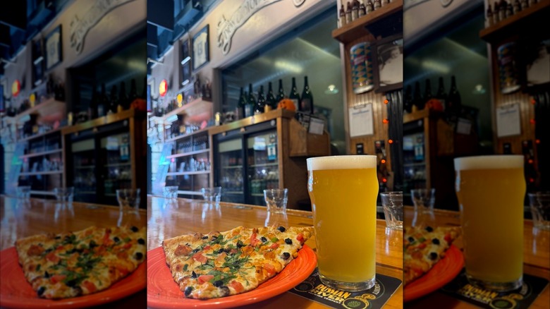 A beer and a pizza slice on a bartop at Russian River