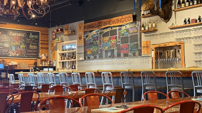 Empty interior of Forager Brewery with chalkboard beer menu and stools lined up at bar counter