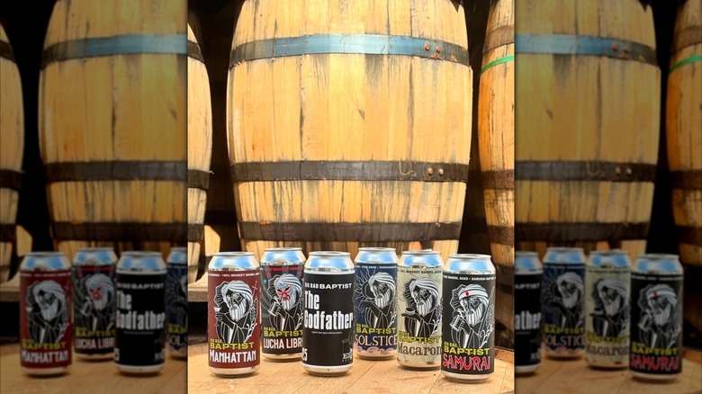 Cans of Epic Brewing tallboy beers in front of wooden barrels