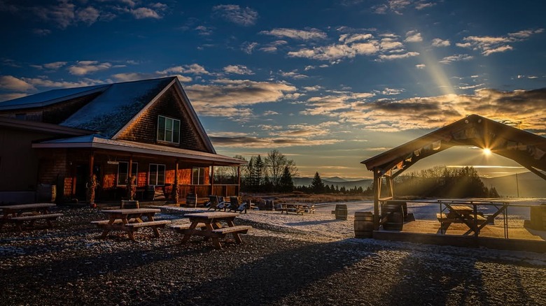 Exterior of Hill Farmstead Brewing with outdoor picnic tables at sunset