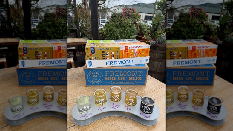 A beer flight in front of packaged beer on outdoor table from Fremont Brewing Company