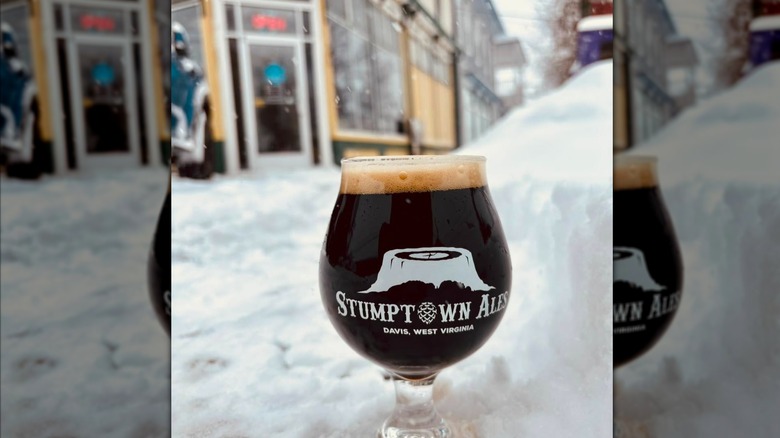 A glass of dark beer in the snow in front of Stumptown Ales
