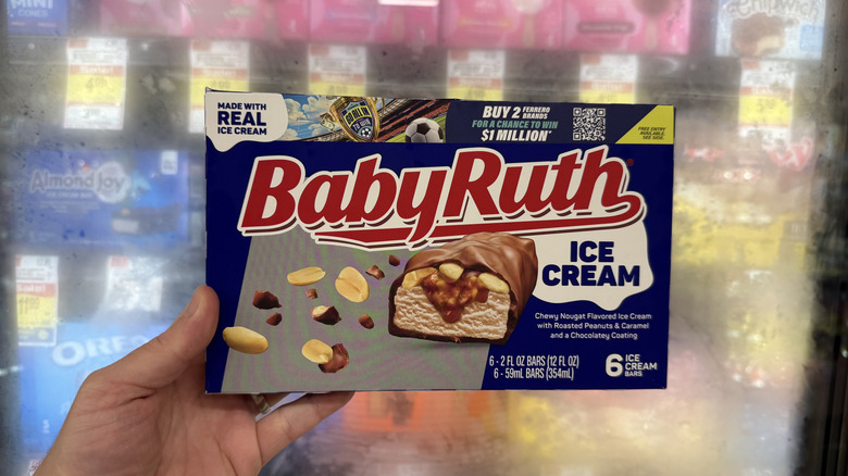 Hand holding package of Baby Ruth ice cream bars in front of freezer display.