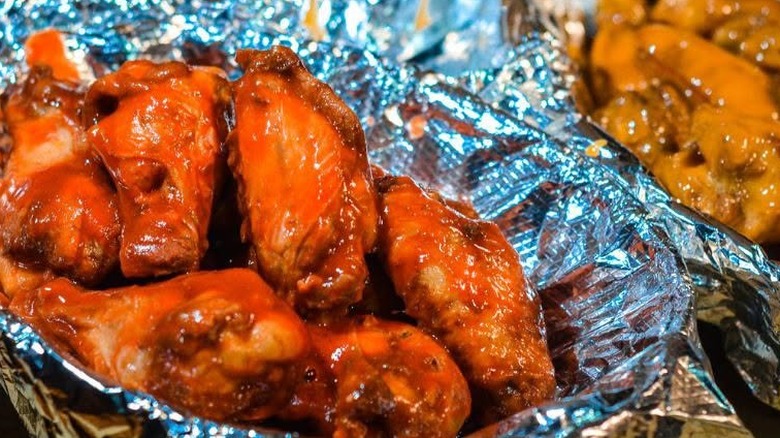 Two tin foil lined baskets of chicken wings tossed in sauce