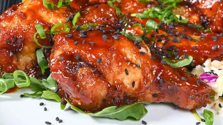 Pile of saucy wings with scallions and sesame seeds